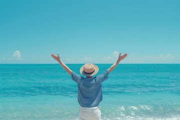 Obraz premium Young teenager with her arms raised in joy, standing on the beach facing an ocean view under clear blue skies.