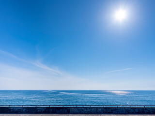 海岸の公園から見る輝く太陽と青空と海