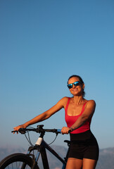 outdoor pursuit. healthy lifestyle concept. a woman with a sports bike in glasses on the beach against the background of the sky and mountains