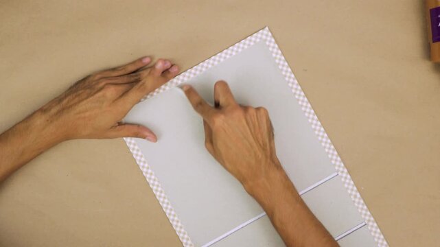 Person carefully crafting a hand-bound book with precise tools and materials, close-up, indoors