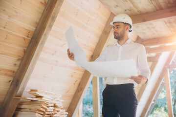 Architect wooden buildings. Man stands under frame wooden house. Man architect studies...