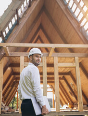 Fototapeta premium Man builder. Rear view of foreman with laptop. Contractor for construction company. Architect in unfinished building. Builder in wooden house under construction. Man engineer from construction team