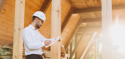Construction engineer in white helmet. Developer with construction documentation on the background...