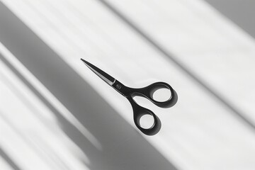 A minimalist arrangement of a sleek, modern pair of black scissors resting on a pristine white surface, casting a subtle shadow that creates a play of light and shadow