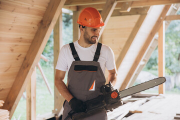 Man worker in work uniform and gloves working with chainsaw of woodcutter sawing chain saw in...