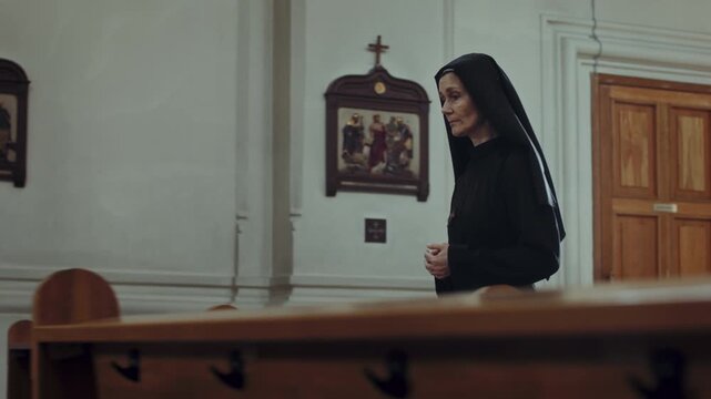Tracking shot of adult Caucasian cloistress in black frock serving in Catholic church