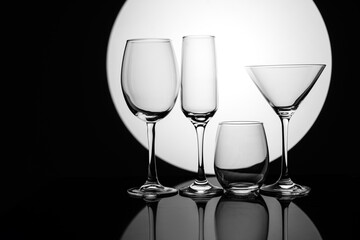 Silhouetted glassware against a glowing orb, reflecting on a surface