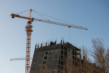 Construction site with cranes and scaffolding against a clear sky, indicating ongoing urban...