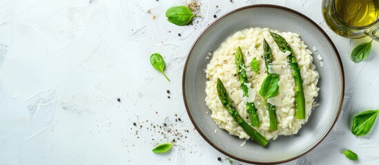 Top down view of Italian risotto with fresh spring asparagus and parmesan cheese served on a plate against a bright background providing space for additional elements in the image
