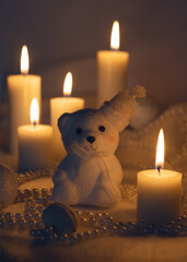 White bear with a hat, surrounded by lit candles, beads, and baubles in a cozy, festive setting