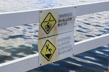 warning signs for shallow water and slippery surfaces at seaside