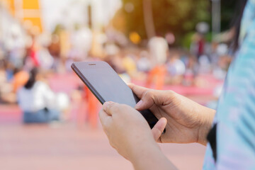 Close-up image of female hands using smartphone at city shopping street