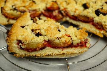 homemade crumble pie close up on cake server and grey backgroud - traditional german crumble cake zwetschgenkuchen close up on cake lifter