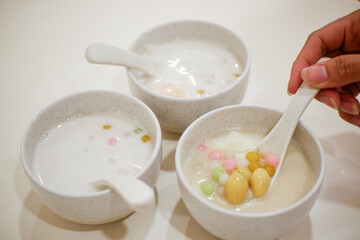 Color Rice Dumpling in Coconut Milk (Bua Loy) in bowl on wooden table.