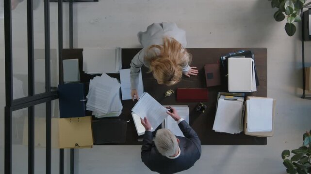 Time lapse top down shot of business people sorting documents at office desk and communicating with boss during workday in law firm