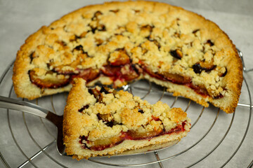 homemade crumble pie close up on cake server and grey backgroud - traditional german crumble cake zwetschgenkuchen close up on cake lifter