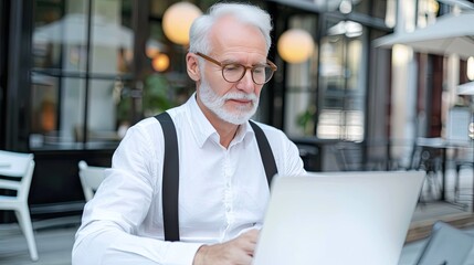 The Elderly Gentleman Is Busy at Work on His Laptop While Sitting at an Outdoor Cafe