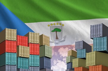 Equatorial Guinea flag and big stack of shipping cargo containers in docks with sky background close up