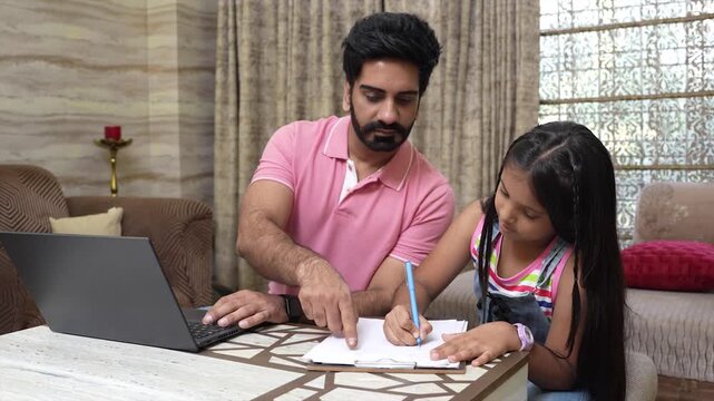 Young indian father helping little daughter with her studies while working on laptop, Multitasking. Education. Girl doing homework while dad work from remote office.