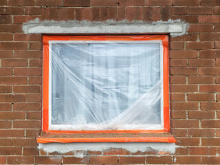 House renovation - brick built 1960's house with new lintel over window and plastic protection over window.