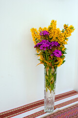 Yellow flowers in a transparent vase, still life background.