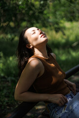 Asian woman with sunlight on face sitting on bench in park