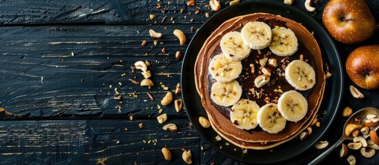Delicious thin pancakes with chocolate paste sliced banana and nuts on a black wooden background set against a blank space for text or images. Creative banner. Copyspace image
