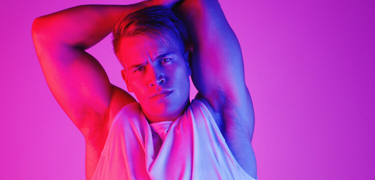 Portrait, health and man stretching arm for fitness or wellness isolated on neon light background space. Face, sport athlete and warm up muscle to get ready for flexibility exercise in studio banner