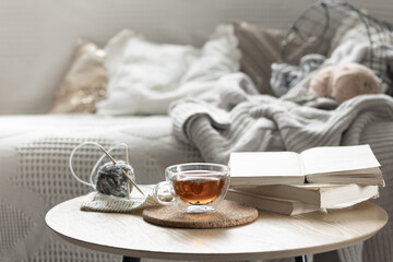 Cozy composition with a cup of tea, a candle and knitted elements.
