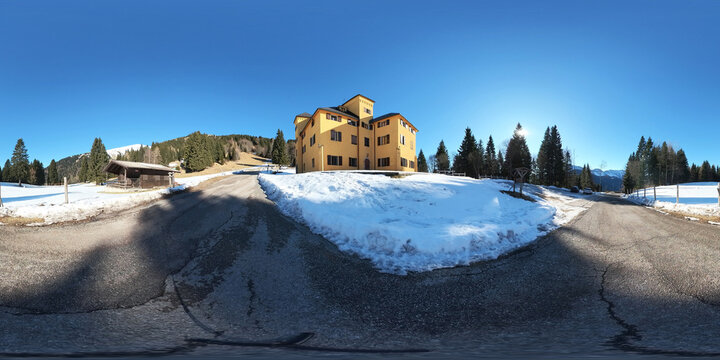 immagine panoramica equirettangolare, a 360 gradi, di un ambiente naturale di montagna innevato nel nord est Italia, di giorno, in inverno, sotto un bellissimo cielo sereno