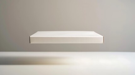 Fototapeta premium A white cardboard box is suspended mid-air against a neutral background, ideal for showcasing packaging design, product delivery, or e-commerce concepts,
