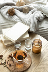 Still life with a cup of tea, books and a candle in a candlestick.