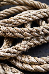 Detailed view of intertwined beige and brown ropes on a textured surface

