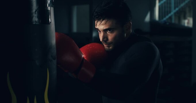 Super slow motion close up of determined sporty male athlete is fisting punching bag during boxing workout and kickboxing training to maintain healthy lifestyle fitness goals in a gym at 1000 fps.