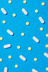 White and yellow tablet pills on blue background.