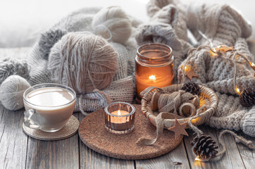 A cozy composition with threads, a candle and a cup of coffee. Hobby and home comfort concept.