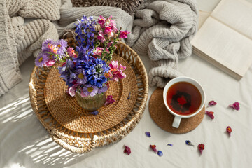 Still life with a cup of tea and a bouquet of wildflowers in a home interior.