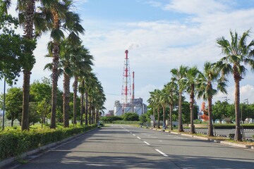 道路の正面の工場の煙突が見える景色