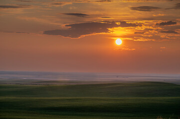 Sun setting behind rolling hills on the prairie at the Great Sandhills, Saskatchewan, Canada