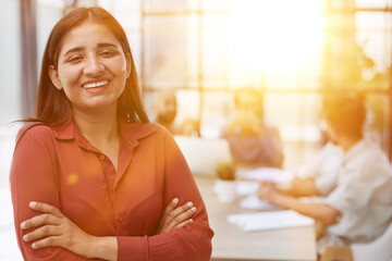 Fototapeta premium Smiling beautiful female professional manager standing with arms crossed looking at camera