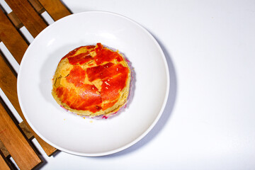 Round bean cake is served on a white plate with a square wooden coaster