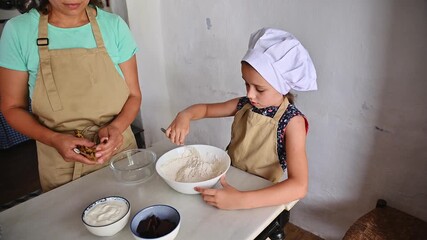 Child in chef hat and apron mixing ingredients in kitchen with guidance