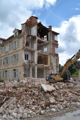 Fototapeta premium A building is being demolished with a large excavator