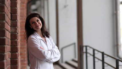 A woman in a casual white jacket stands with arms crossed, exuding a calm and approachable demeanor. This photo highlights the importance of taking moments to reflect and appreciate personal growth.