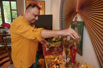 Mature Indian man praying at altar at home