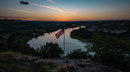 Obraz premium Scenic sunset over a bridge and river with an american flag fluttering in the wind