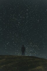 Fototapeta premium A man stands on a hill at night gazing at the starry sky and the milky way galaxy, creating a peaceful scene of the vastness of nature.