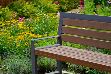 drewniana ławka ogrodowa w ogrodzie z kolorowymi kwiatami, wooden garden bench in the garden with colorful flowers, garden seating area © kateej