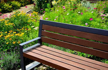 drewniana ławka ogrodowa w ogrodzie z kolorowymi kwiatami, wooden garden bench in the garden with colorful flowers  © kateej