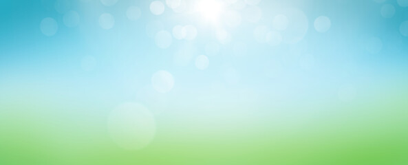 A fresh, bright but warm spring and summer blue sky background with sun flare in the centre over blurred green foliage.